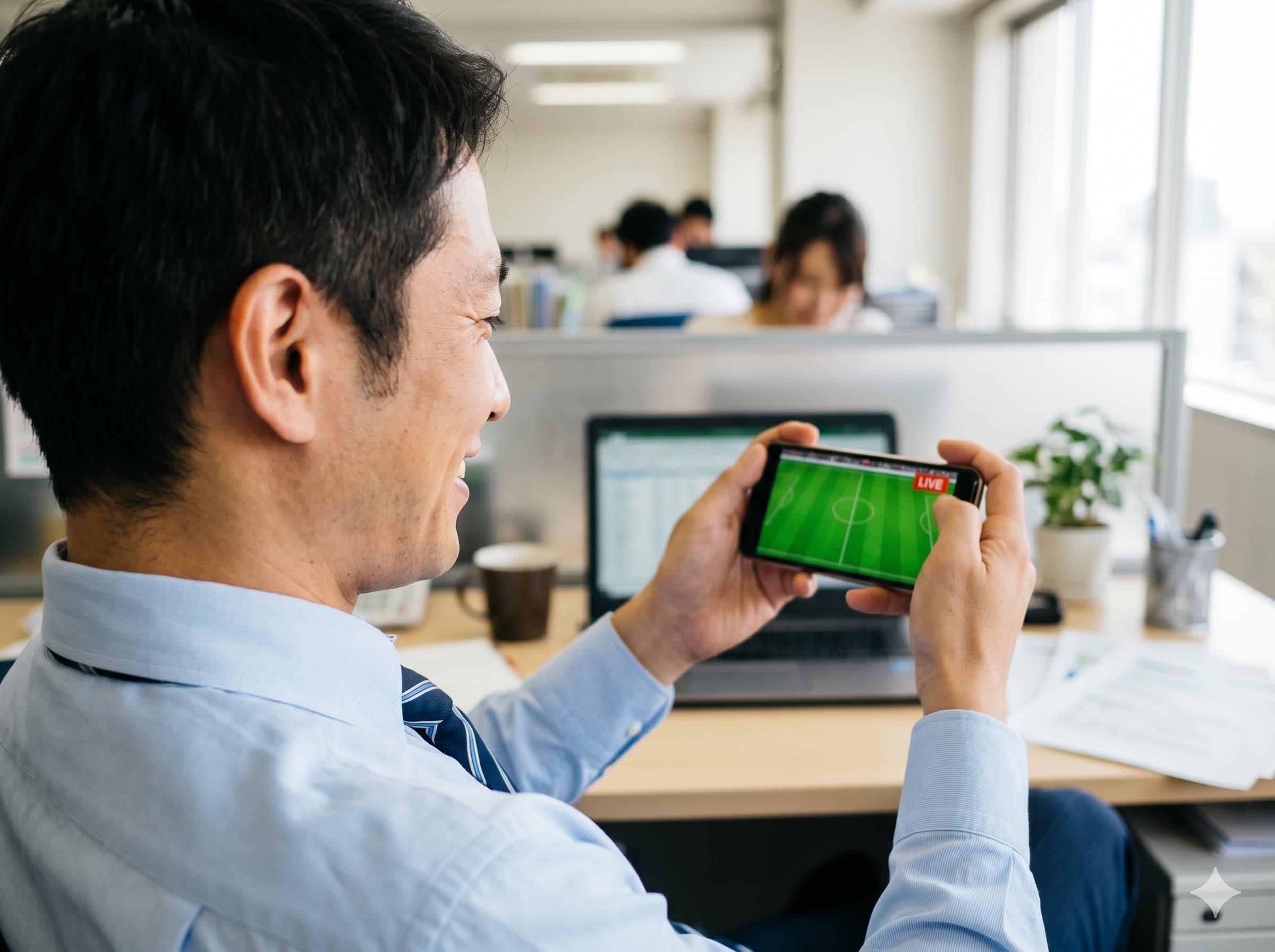 仕事中の父親がオフィスからスマホで子どもの試合をライブ観戦